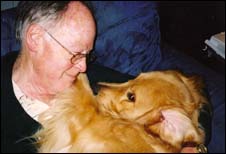 Man cuddling with a golden retriever dog.