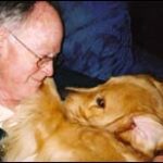 Man cuddling with a golden retriever dog.